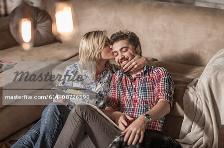 Woman with vinyl record kissing man at home