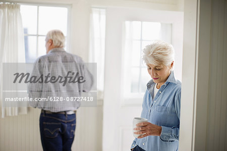 Mature adult couple standing having a drink in a room.