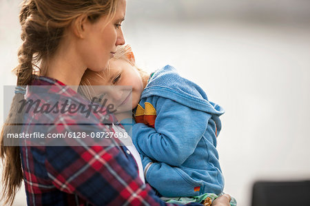 Smiling little girl snuggles happily in her mother's arms.