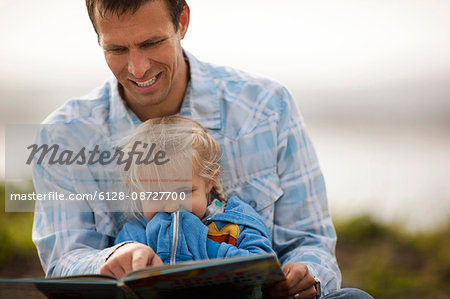 Smiling father enjoys reading a storybook to his little girl.