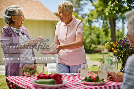 Happy senior friends enjoying a healthy lunch outside.