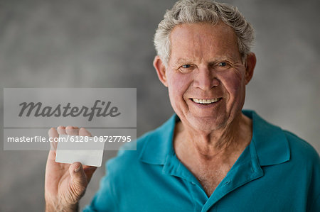 Portrait of a smiling elderly man holding a blank card.