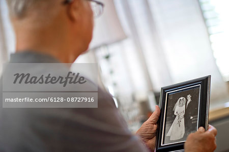 Senior man looking at an old wedding photo.