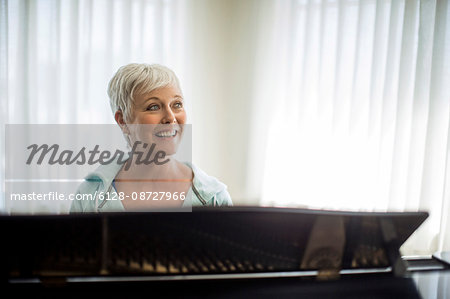 Portrait of a cheerful mature woman preparing to play the piano.