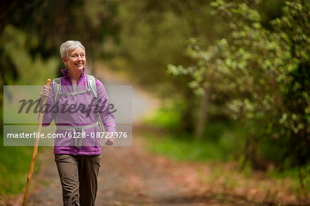 Happy mature woman enjoys a peaceful hike through the woods.