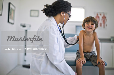 Doctor listening to a young boy's heartbeat with a stethoscope.