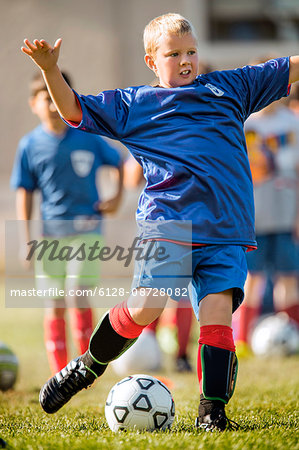 Young boy kicking a ball during a soccer game.