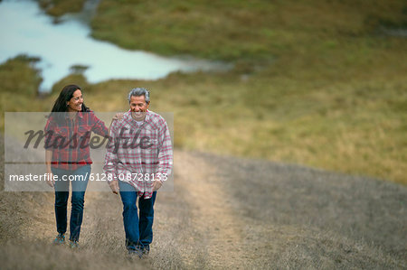 Mature couple walking on a grassy path.