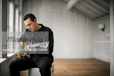 Teenage boy playing his electric guitar.