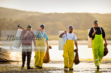 Group of fisherman on the beach with bags of shellfish.