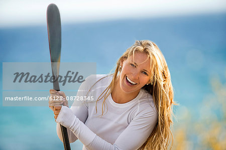 Happy young woman holding her paddleboard oar.