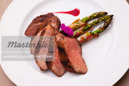 Grilled duck breast with bacon asparagus and raspberry sauce