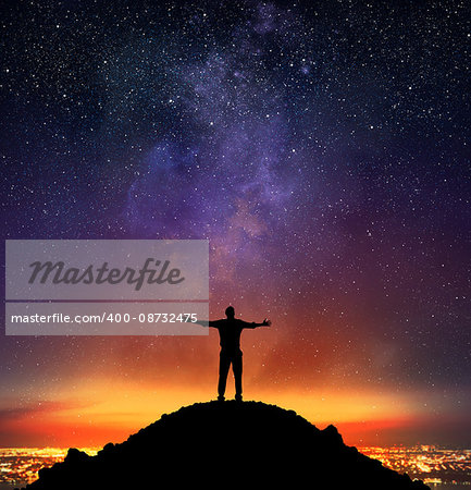 Businessman exults on a mountain with starry sky background