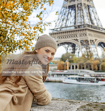 Autumn getaways in Paris. Portrait of smiling young tourist woman on embankment in Paris, France