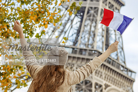 Autumn getaways in Paris. Seen from behind young elegant woman on embankment in Paris, France rising flag