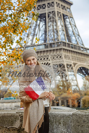 Autumn getaways in Paris. smiling young elegant woman on embankment in Paris, France with flag