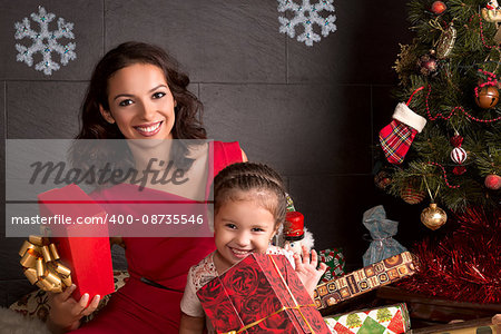 Happy mother with small daughters open a Christmas gift