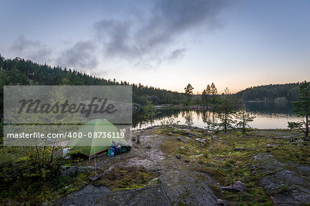 Late evening landscape view of Ladoga lake islands and small tourist tent on the rocks. Karelia, Russia.