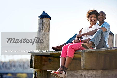 Couple sitting together on wharf.