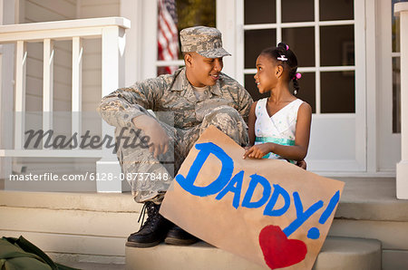 Young girl and her father having a discussion on the front porch of their home.
