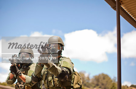 Two police officers point a gun towards a target during an exercise at a training facility.
