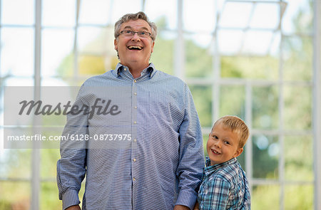 Smiling mature man standing next to grinning grand son.