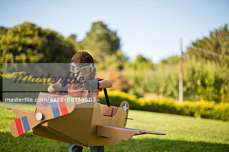 Young boy having fun pretending to be a pilot in a cardboard plane.