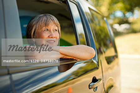 Happy senior woman looking out the window of a SUV.