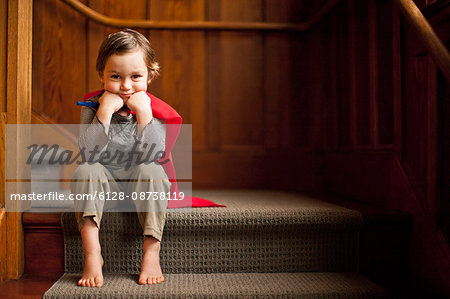 Young boy wearing a superhero cape.