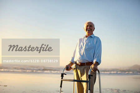 Portrait of a senior man standing on a beach with a walking aid.
