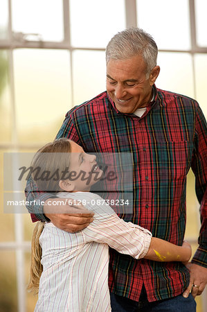 Smiling young girl hugging her grandfather.