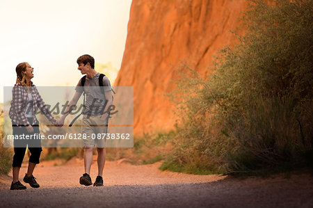 Happy young couple having fun while hiking hand in hand through a desert.