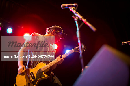 Teenage boy playing an electric guitar on stage.