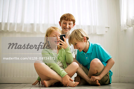 Smiling young siblings playing with a smart phone.
