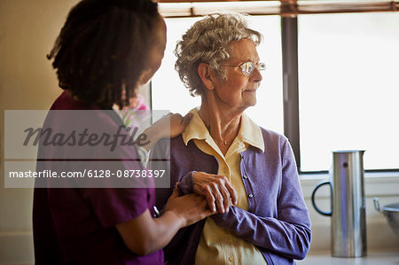 Young nurse comforting a grieving senior woman.