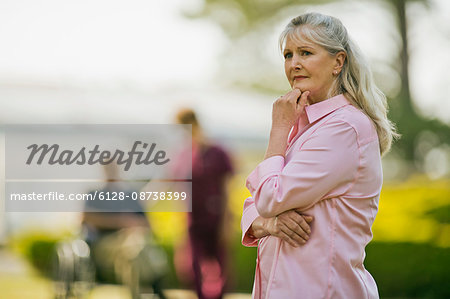 Concerned senior woman standing with her hand on her chin. Concerned senior woman standing with her hand on her chin.