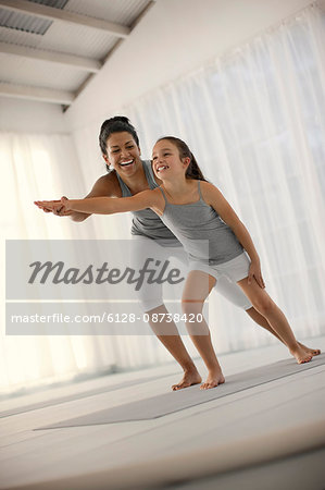 Smiling young woman showing a young girl how to stretch her arm.