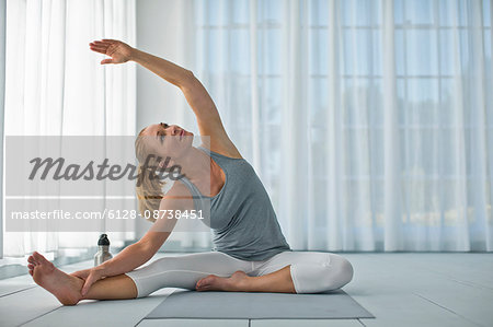 Happy mid adult woman stretching her arms and legs while practicing yoga.