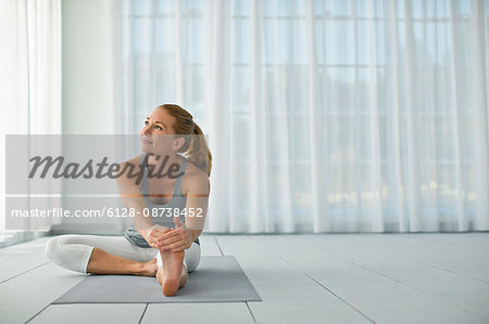 Thoughtful mid adult woman stretching while practicing yoga.