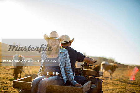 Portrait of a woman riding on the back of her husband's quad bike out on the ranch.