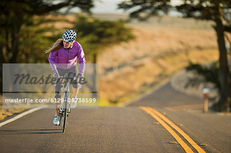 Focused young woman cycling down a lonely country road.