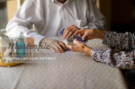 Elderly couple enjoy playing cards together at the kitchen table.