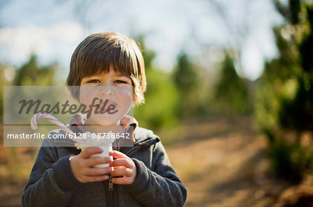 Portrait of a happy young boy licking his lips as he enjoys a sweet treat on his visit to the Christmas tree farm.