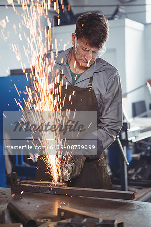 Welder cutting metal with electric tool in workshop