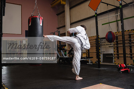 Man practicing karate with punching bag in fitness studio