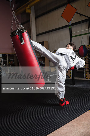 Man practicing karate with punching bag in fitness studio