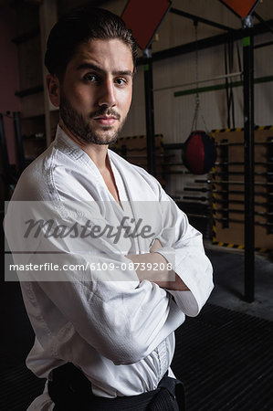 Portrait of man in karategi standing with arms crossed in fitness studio