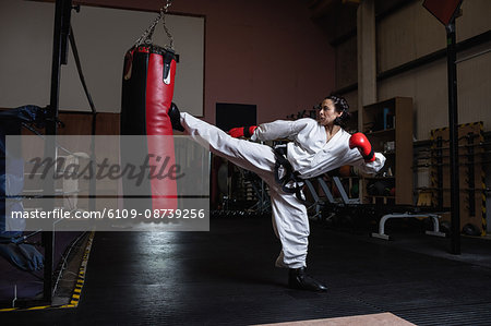 Woman practicing karate with punching bag in fitness studio