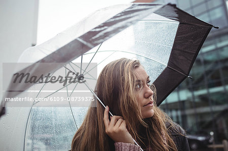 Beautiful woman holding an umbrella during rainy season on street