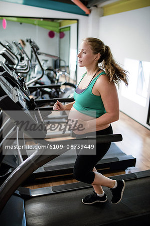 Pregnant woman exercising on treadmill at gym